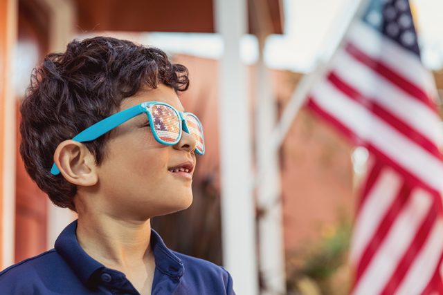 Patriotic Boy Holding an American Flag Outside his Home