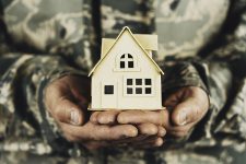 Military service member holding little cardboard house